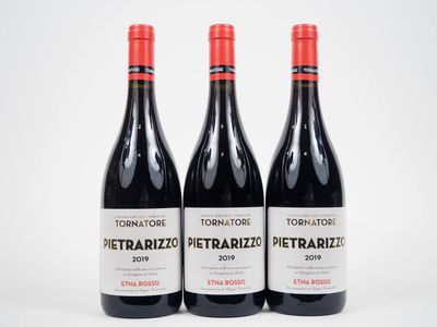trois bouteilles de vin rouge posées l'une à côté de l'autre sur une surface blanche