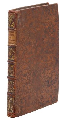 an old book with a brown cover sitting on top of a white surface