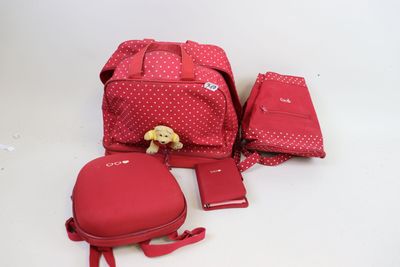 plusieurs bagages posés sur une surface blanche, avec un ours en peluche