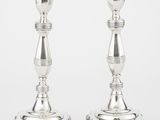 paire de bougeoirs plaqués argent sur un socle, sur fond blanc