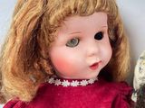 two dolls sitting next to each other on a white surface