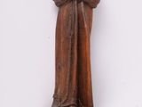 une statue en bois représentant une femme coiffée d'un chapeau, posée sur une étagère