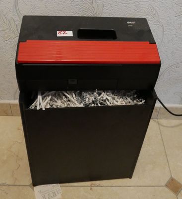 une déchiqueteuse de papier rouge et noire posée sur un sol carrelé