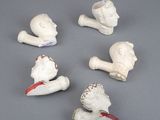 six white ceramic figurines of a man and a woman on a gray surface