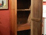 a tall wooden cabinet in a room with pictures on the wall