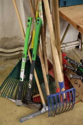 un tas d'outils de jardinage posé par terre à côté d'une table