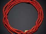 un gros plan sur un collier de perles rouges muni d'un fermoir doré