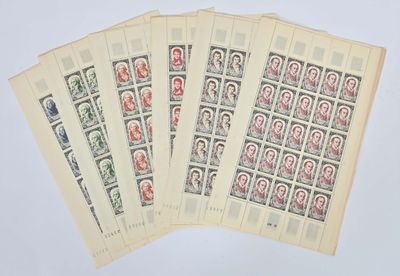 quatre vieux timbres représentant des personnes, sur une feuille de papier posée sur une surface blanche