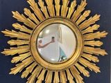 a gold sunburst mirror hanging on a blue wall