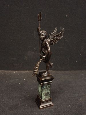 statue d'un ange tenant un balai, posée sur un socle, sur fond noir