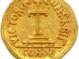 a close up of a gold coin with a cross on it