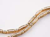 a close up of a gold and diamond necklace on a white surface