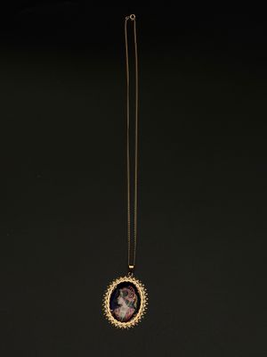 un collier plaqué or sur lequel est représentée une femme