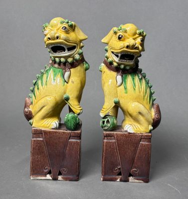 pair of yellow and green foo foo figurines sitting on top of a wooden box