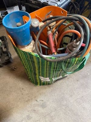 un panier rempli d'outils posé par terre dans le garage