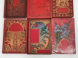 four red books with gold designs on them sitting on a white surface