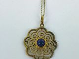un gros plan sur un collier en or orné d'une pierre bleue au centre