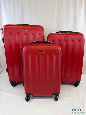 trois valises rouges posées sur une surface blanche