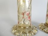 two glass vases with flowers on them on a white surface