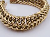 a close up of a gold bracelet on a white surface