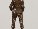 bronze statue of a boy standing with his back to the camera
