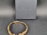a gold bracelet with a flower design on it next to a box
