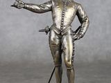 statue en bronze représentant un homme muni d'une épée et portant un chapeau, posée sur un socle