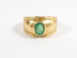a close up of a gold ring with a green stone