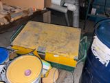 une boîte jaune posée sur une table, à côté de deux fûts bleus