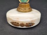 a white and gold box with a green stone in it