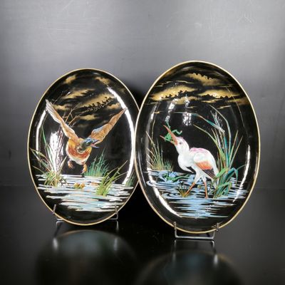 two plates with birds painted on them sitting on a table