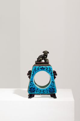 une horloge bleue posée sur un socle blanc dans une pièce