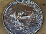 a metal plate with a picture of a man in a boat on it