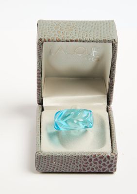 une bague en verre bleu dans une boîte posée sur une surface blanche
