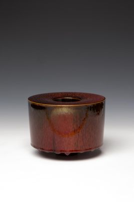 une image représentant un bol marron et noir posé sur une surface blanche