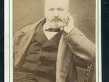 une vieille photo d'un homme assis sur une chaise, la main posée sur le menton