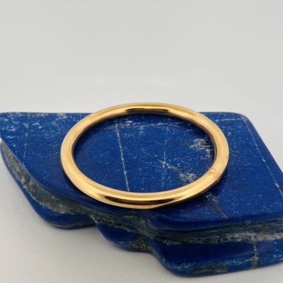 un gros plan d'une bague en or posée sur une pierre bleue