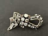 an image of a silver bow brooch with crystals on it