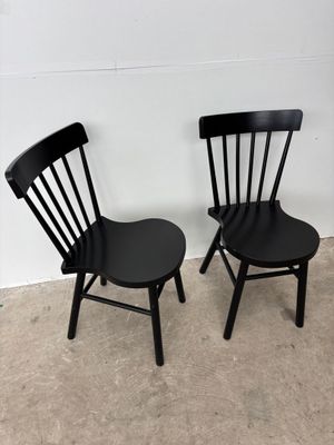 pair of black wooden chairs against a white wall in a room