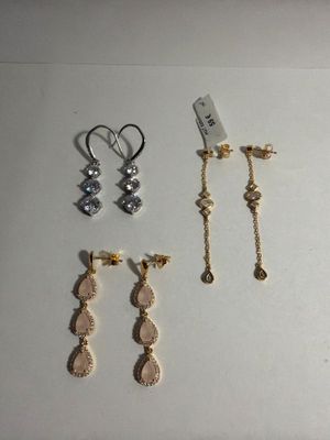 three pairs of gold and silver earrings on a white surface