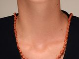 une photo d'une femme portant un collier composé de perles orange