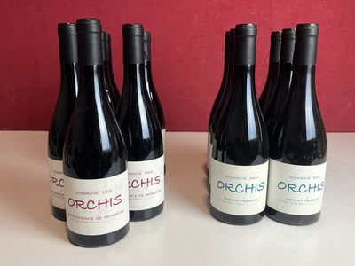 trois bouteilles de vin rouge sont posées sur une table devant un mur rouge