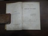 un livre ouvert posé sur une table en bois, à côté d'un étui en cuir
