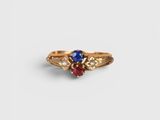 un gros plan d'une bague en or sertie d'une pierre bleue et rouge