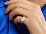 the woman is wearing a gold ring with a white flower on it