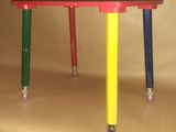 a small table with three legs that are painted red, yellow, green, and blue