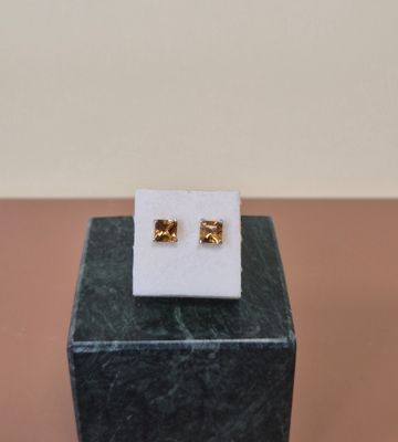 une paire de boucles d'oreilles en or posée sur un bloc de marbre