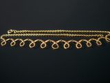 a close up of a gold chain bracelet on a black background