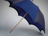 un parapluie bleu avec un manche en bois sur fond gris