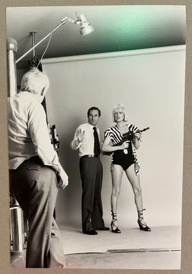 photographie en noir et blanc de deux hommes et d'une femme debout devant un appareil photo
